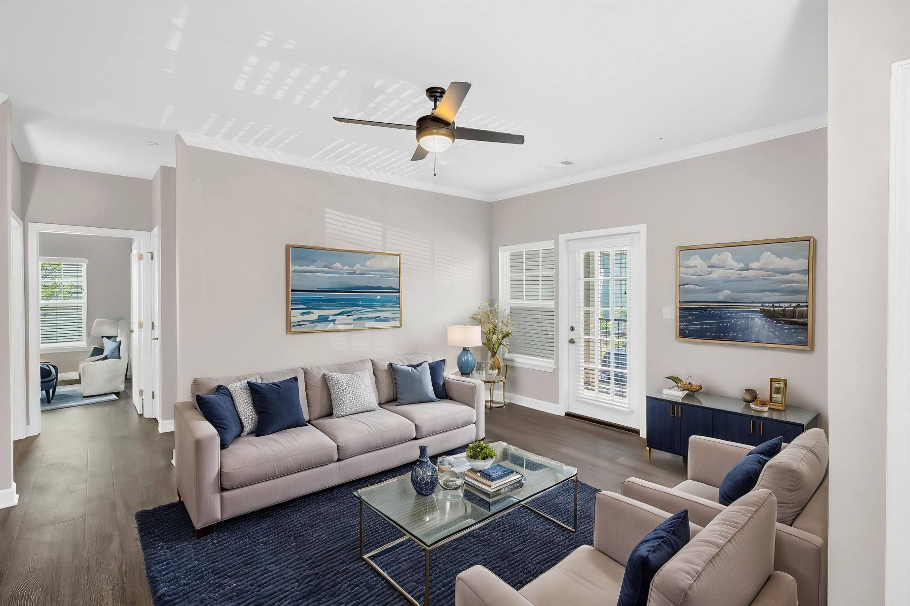 Empty room with wood floors, ceiling fan, and sliding glass door leading to a patio with vertical blinds at Apex West Midown.